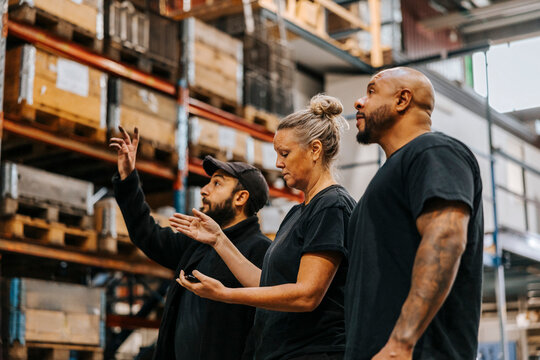 Low angle view of male and female distribution worker discussing while standing in warehouse