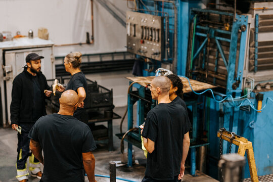 High angle view of male and female factory workers discussing with each other