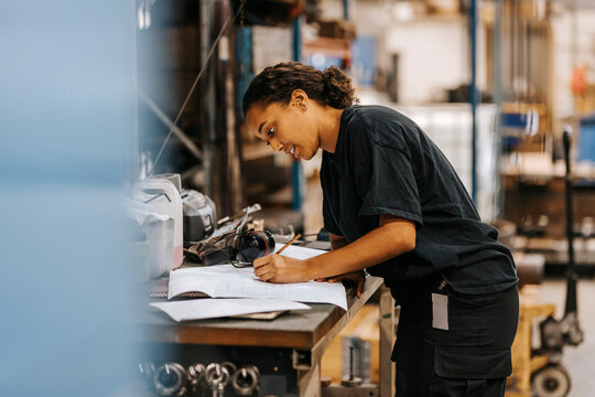 Female warehouse professional writing on document at table