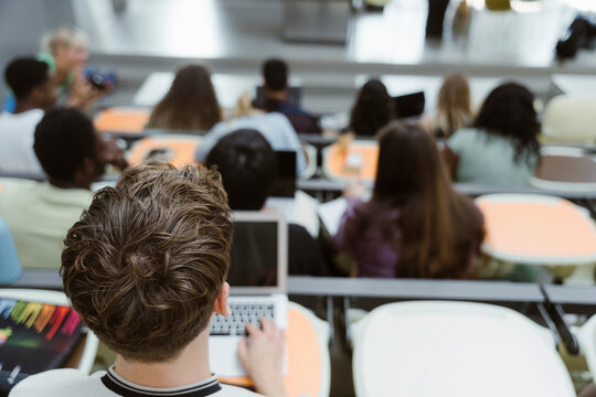 High angle view of male student sitting with laptop in lecture hall at university