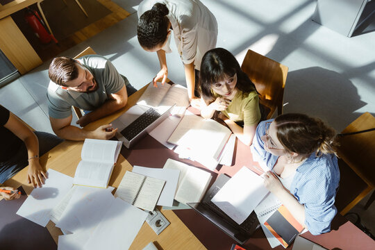 High angle view of multiracial male and female university students doing group assignment in library at college