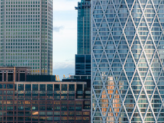 The image captures a close up of skyscrapers in Canary Wharf, London, featuring a building with a crisscross facade among glass and steel structures.