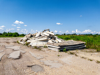 The scene showcases a view of an abandoned site featuring stacked concrete debris beneath a clear, blue sky