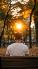 Fototapeta premium Serene Morning Meditation: Mindful Man Listening to Guided Meditation on Phone with Wireless Headphones in Park at Sunrise for Digital Wellness