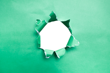 Torn holes in green paper on a blank white background