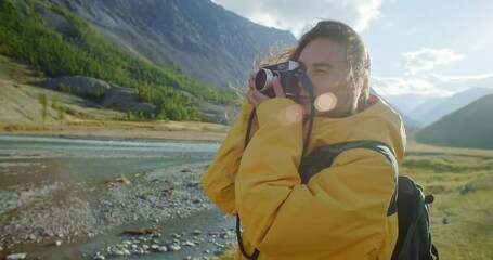 Female photographer taking pictures with vintage camera of a stunning river landscape under vibrant skies
