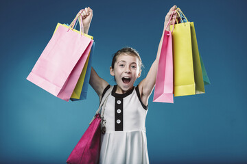 Enthusiastic girl holding shopping bags and smiling at camera