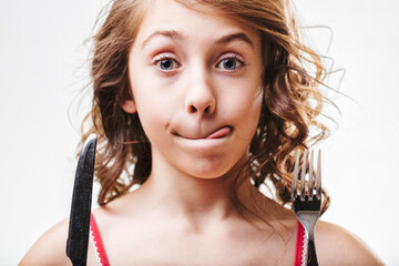 Young girl anticipating a meal with utensils