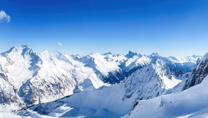 Obraz premium A panoramic view of majestic snow-covered peaks stretching across the horizon under a clear blue sky, with crisp, vivid details capturing the serene alpine landscape.