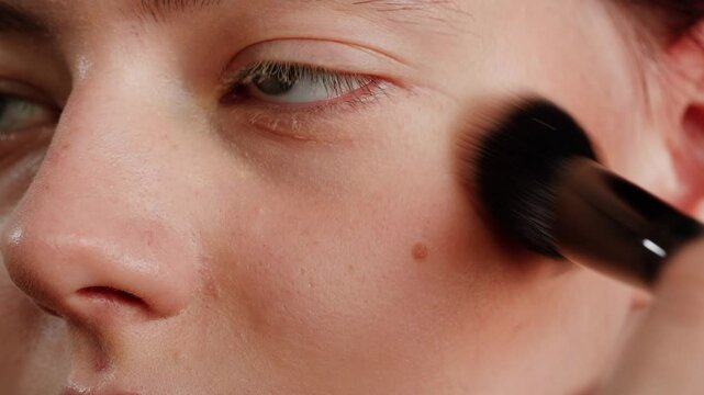 Beauty shot of woman makeup artist applying foundation bb cream on previously applied moisturizing young woman face close-up. Concept of skincare, cosmetics, make up, beauty