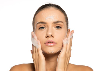 Young beautiful woman washing her face in soap foam.