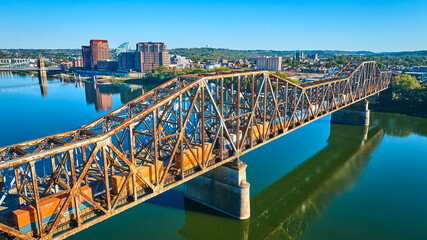Fototapeta premium Aerial of Rusted Steel Truss Bridge and Train Over Ohio River at Sunrise