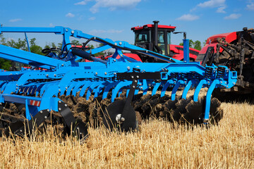 Many a large tractor with a plow in a field. Start tillage after harvest.