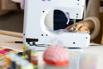 A woman who is running an online clothing business and is also a designer, working on designing clothes and preparing them to be packed in boxes to be delivered to customers.