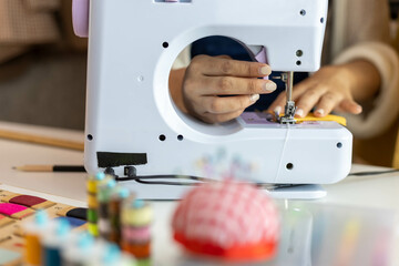 A woman who is running an online clothing business and is also a designer, working on designing clothes and preparing them to be packed in boxes to be delivered to customers.