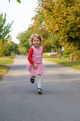 Fototapeta premium A child runs and jumps on the street along the road. Selective focus.