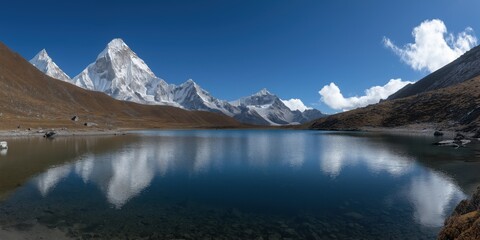 Crystal clear lake reflecting snow-capped mountains beneath a vibrant blue sky and picturesque clouds.