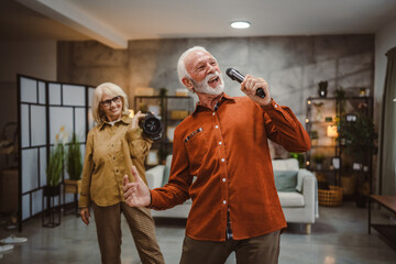 senior man sing karaoke on microphone with senior woman dance behind