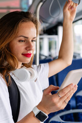 Vertical portrait of urban woman traveling by bus and using her smartphone.