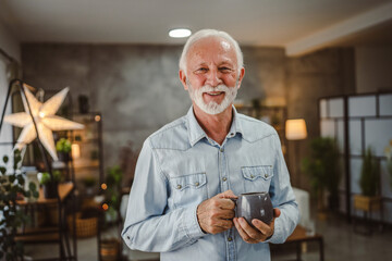 portrait of senior man stand with mug and enjoy at his coffee at home