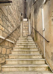 Korcula, Croatia - June 30, 2024: Steps leading higher while becoming narrower as a triangle is created by two house walls on Prolaz Tri Sulara square