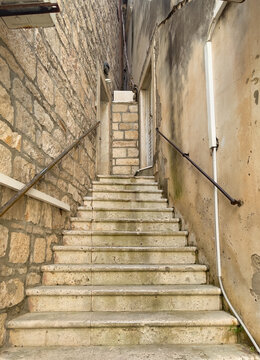 Korcula, Croatia - June 30, 2024: Steps leading higher while becoming narrower as a triangle is created by two house walls on Prolaz Tri Sulara square