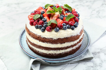 Delicious chocolate sponge cake with berries on white table, closeup