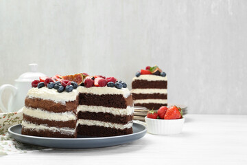 Delicious chocolate sponge cake with berries served on white wooden table