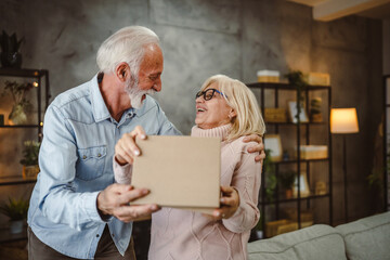 senior husband give gift box to her senior wife at home