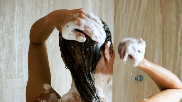 Woman washing hair with shampoo and shower in bathroom, hair care with foam to freshness. Spa and Health care.