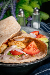 Wholegrain tortilla wraps with vegetables and chicken on a plate.