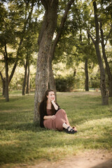 Girl in nature in the park. Curly girl in a linen dress. Sunny day and beautiful sunlight. Warm photos of a girl enjoying nature in a good mood. Walking alone with yourself and the beauty of nature.