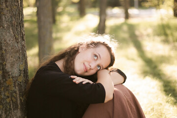 Girl in nature in the park. Curly girl in a linen dress. Sunny day and beautiful sunlight. Warm photos of a girl enjoying nature in a good mood. Walking alone with yourself and the beauty of nature.