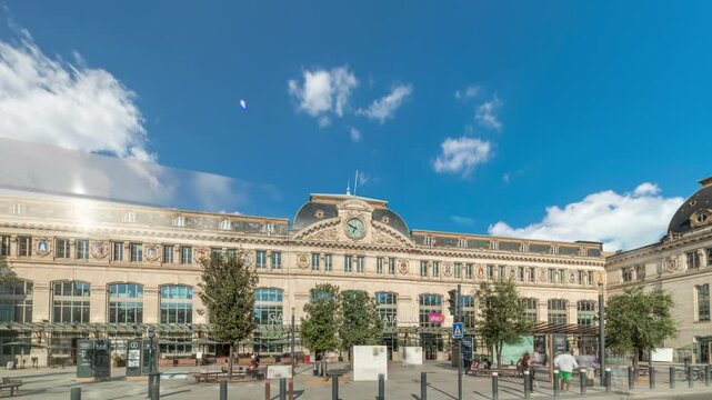 Monumental facade of Gare de Toulouse-Matabiau timelapse hyperlapse, featuring a clock, big windows and flags. The central railway station of Toulouse, France, under cloudy skies with road traffic