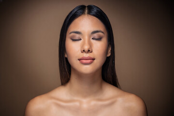 Beautiful young woman posing to camera on isolated brown background