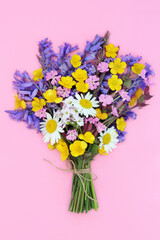 Spring wildflower bunch bluebells, buttercups, red campion, meadow grass, daisy flowers on pink. Flower bouquet arrangement gift for birthday, mothers day, Beltane.