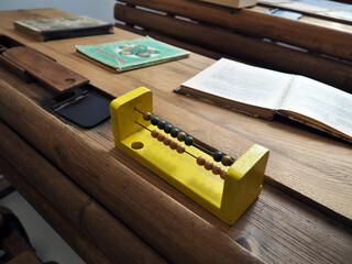 An old school desk with an old wooden abacus on it.