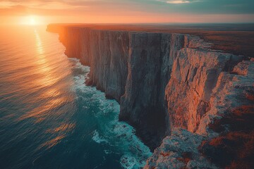 Stunning sunset over the dramatic cliffs by the ocean highlighting vibrant colors in the sky and...