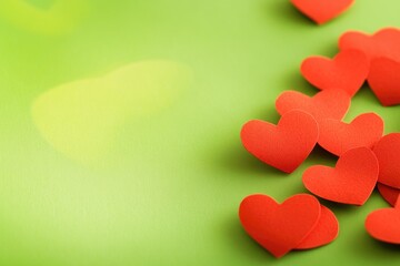A bunch of bright red paper hearts on a green surface, ready for decoration or crafting
