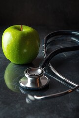 A green apple with a stethoscope placed beside, perfect for health or nutrition illustrations