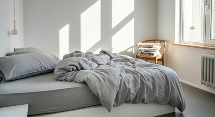 Sunlit bedroom with unmade bed and wooden chair
