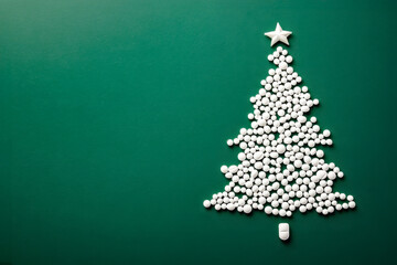 Christmas tree made from pills with copy space on green background