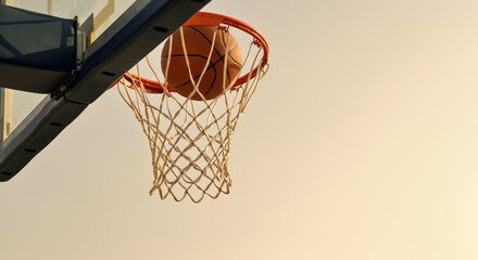 Basketball going through hoop at outdoor court, sunset sky