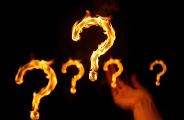 Burning question marks float in dark interior space. Intense flames form question marks against dark background. Room hall implied in scene with empty space. Hand slightly visible in blurred