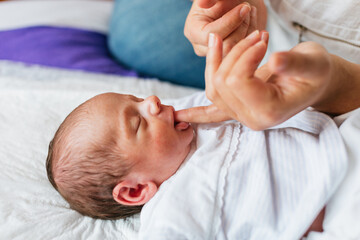 Mother playing with her newborn baby boy at home