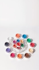 Containers with paints in pastel and bright colors on white background with space for text