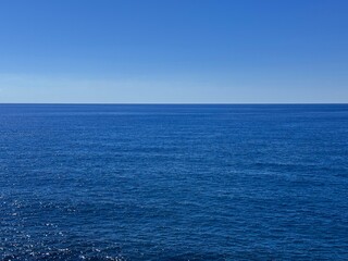 Open sea blue calm water and cloudless sky.