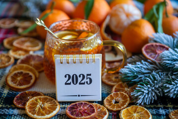 New Year 2025, tea with orange, coffee with marshmallows, books and fir branches, New Year's toys and a ball on the table.