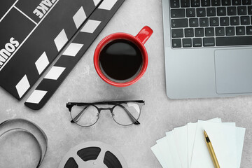 Flat lay composition with movie clapper, film reel and laptop on grey textured table