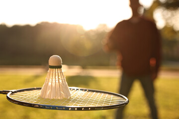 Badminton racket and shuttlecock in park on sunny day, selective focus